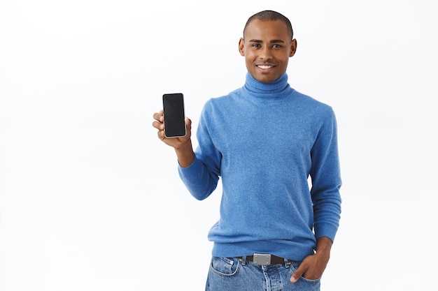 Retrato de um homem afro-americano bonito promovendo o aplicativo, mostrando a tela do smartphone