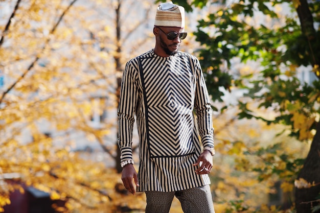 Retrato de um homem afro-americano elegante com chapéu e óculos de sol contra o fundo ensolarado do outono