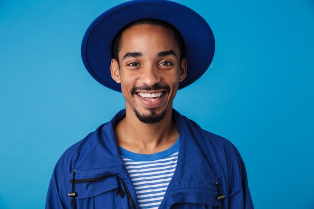 Retrato de um homem afro-americano engraçado com chapéu sorrindo isolado no azul