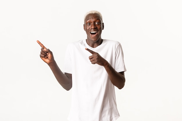 Retrato de um homem afro-americano feliz e animado, olhando fascinado e apontando o dedo no canto superior esquerdo