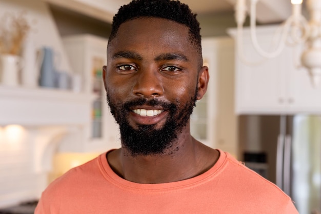 Foto retrato de um homem afro-americano feliz numa cozinha branca. estilo de vida, relaxamento e vida doméstica, inalterados.