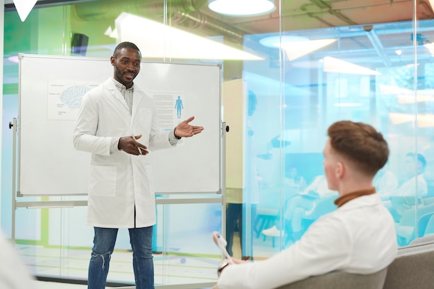 Retrato de um homem afro-americano parado ao lado do quadro branco enquanto faz uma apresentação durante o seminário médico na faculdade, copie o espaço