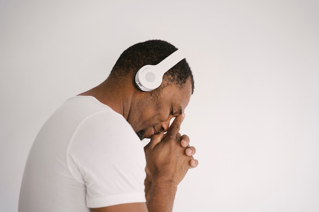 Retrato de um homem afro-americano sorridente, ouvindo música no pensamento de fones de ouvido.