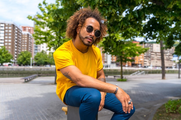Retrato de um homem afrohaired em uma camiseta amarela Retrato na cidade sorrindo nas férias de verão