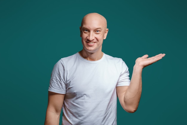 Retrato de um homem alegre careca segurando a mão para o lado mostra um gesto para o lado