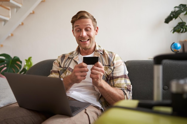 Retrato de um homem alegre indo de férias planeja uma viagem de viagem no exterior tem laptop aberto senta-se em