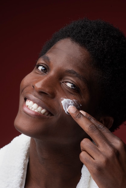 Foto retrato de um homem aplicando hidratante e sorrindo