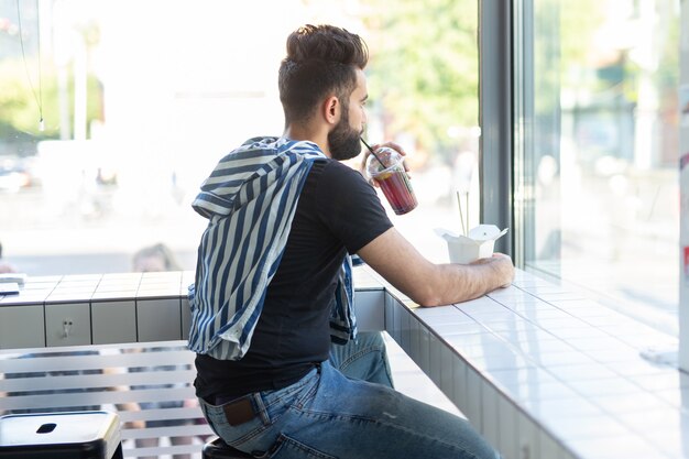 Retrato de um homem árabe bonito, bebendo smoothie em um café. O conceito de bebidas saudáveis e estilo de vida.