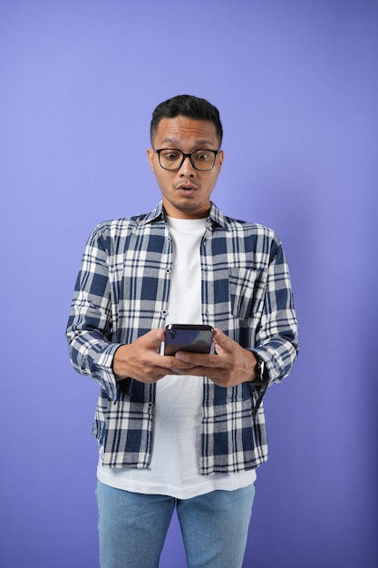 Retrato de um homem asiático alegre segurando e mostrando cartão de crédito e celular com gesto de mão