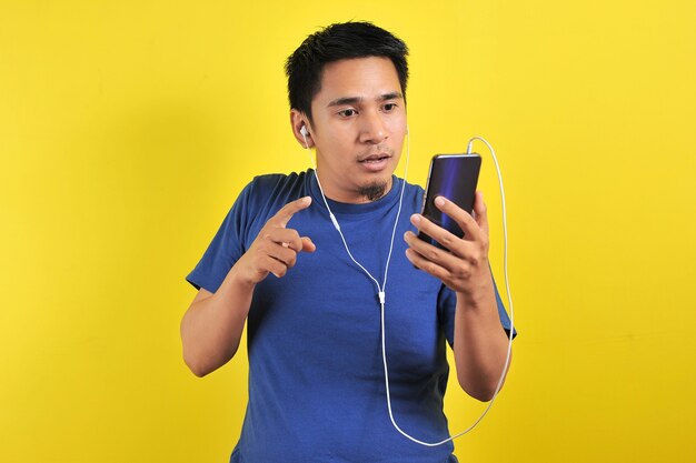 Retrato de um homem asiático empolgado surpreso ao encontrar uma música popular on-line