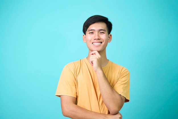 Retrato de um homem asiático feliz e confiante em camiseta amarela em fundo isolado