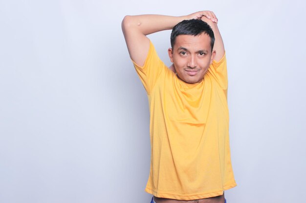 retrato de um homem asiático vestindo uma camiseta amarela esticando os braços fundo branco