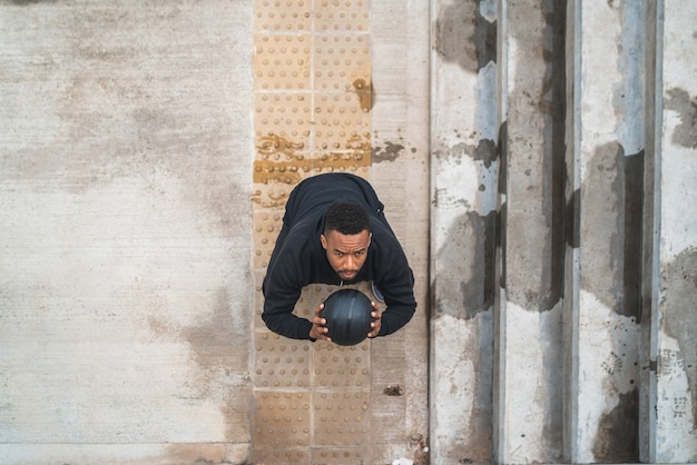 Retrato de um homem atlético fazendo exercícios de bola de parede ao ar livre. esporte e conceito saudável.