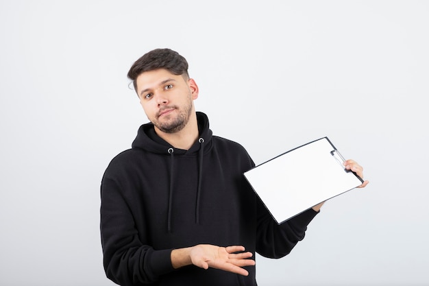 Retrato de um homem barbudo bonito com capuz preto segurando uma prancheta