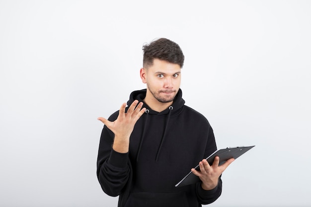 Retrato de um homem barbudo bonito com uma prancheta em pé sobre o branco