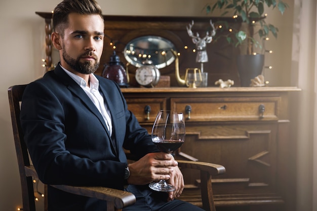 Retrato de um homem barbudo bonito com uma taça de vinho tinto