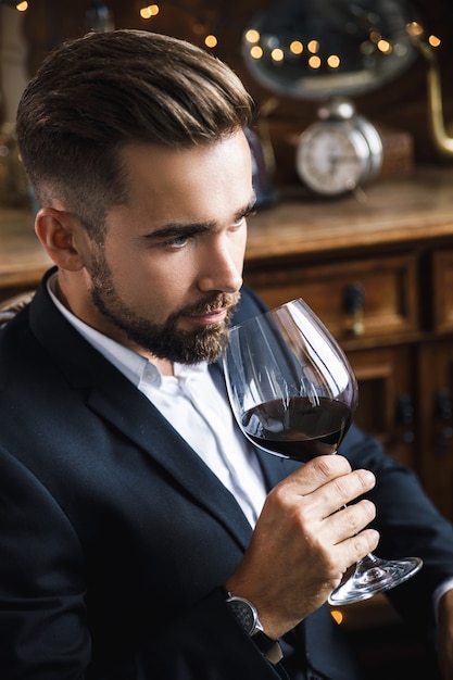 Retrato de um homem barbudo bonito com uma taça de vinho tinto