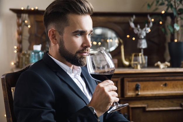 Retrato de um homem barbudo bonito com uma taça de vinho tinto