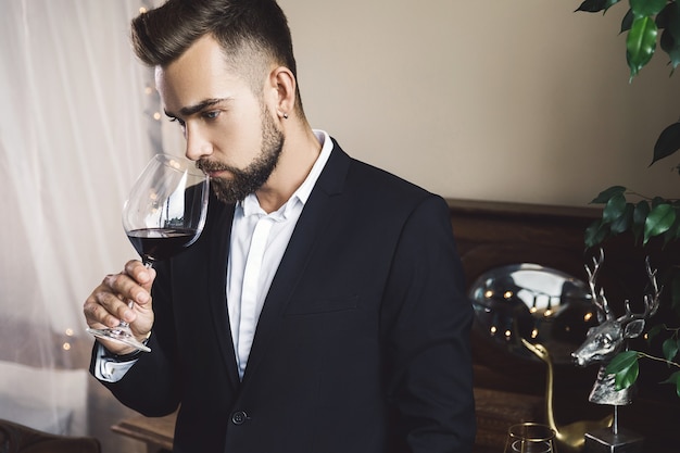 Retrato de um homem barbudo bonito com uma taça de vinho tinto