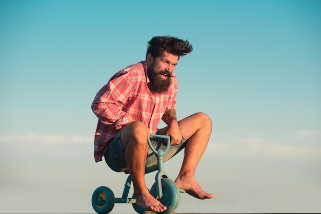 Retrato de um homem barbudo, um ciclista louco, um hippie se divertindo com uma bicicleta ao ar livre