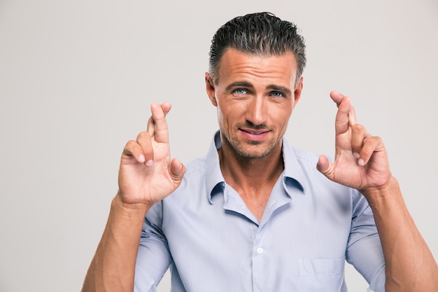 Retrato de um homem bonito cruzando os dedos sobre o espaço cinza e olhando para a cmaera