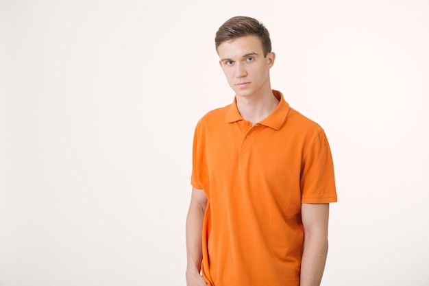 Retrato de um homem bonito de cabelos castanhos vestindo uma camisa laranja e parecendo tranquilo em pé