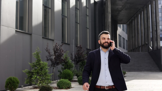 Retrato de um homem bonito e sorridente no casual wear, falando no smartphone.