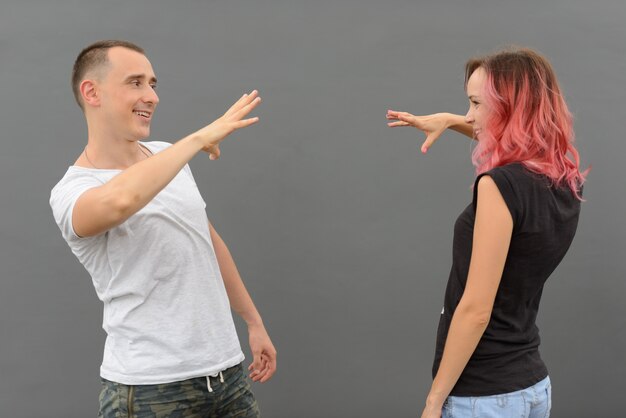 Retrato de um homem bonito e uma linda mulher com cabelo rosa como casal juntos e apaixonados contra uma parede cinza ao ar livre