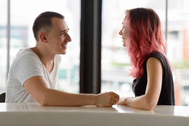 Foto retrato de um homem bonito e uma linda mulher com cabelo rosa como casal no balcão contra a janela de vidro