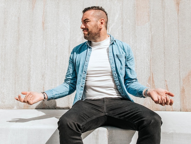 Retrato de um homem bonito hipster em uma jaqueta jeans em uma cidade grande na rua um conceito de estilo de vida