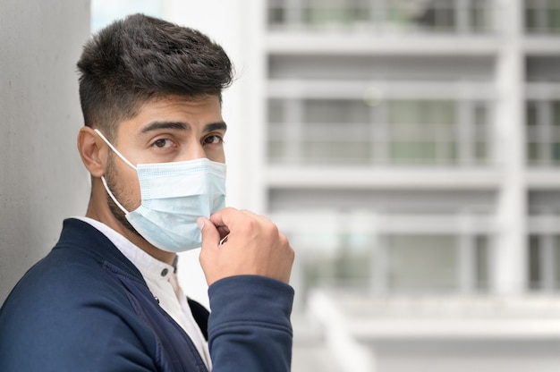 Retrato de um homem bonito na máscara médica, olhando para a câmera na cidade jovem bonito, destacando-se ...