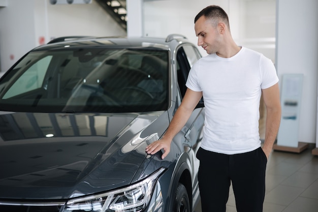 Foto retrato de um homem bonito parado no carro no sapato homem comprando um carro novo