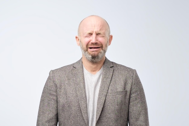 Retrato de um homem caucasiano chorando na barba e terno casual em fundo branco