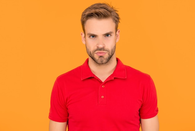retrato de um homem com cerdas em camisa vermelha jovem sério com barba em fundo amarelo cabelo e cuidado da barba bonito homem sem barbear homem moda casual beleza masculina