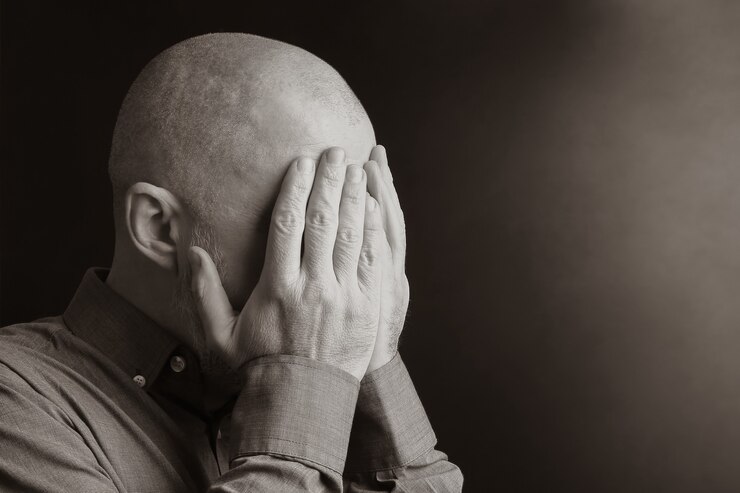Retrato de um homem com o rosto de mãos fechadas. desespero e depressão. vergonha e culpa. tristeza e exílio