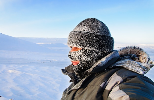 Retrato de um homem com um boné e uma máscara de esqui. inverno com geada.