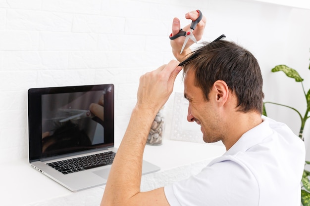 Retrato de um homem cortando o cabelo para si mesmo durante a quarentena