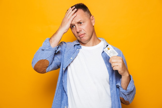 Retrato de um homem de meia-idade chateado segurando um cartão de crédito