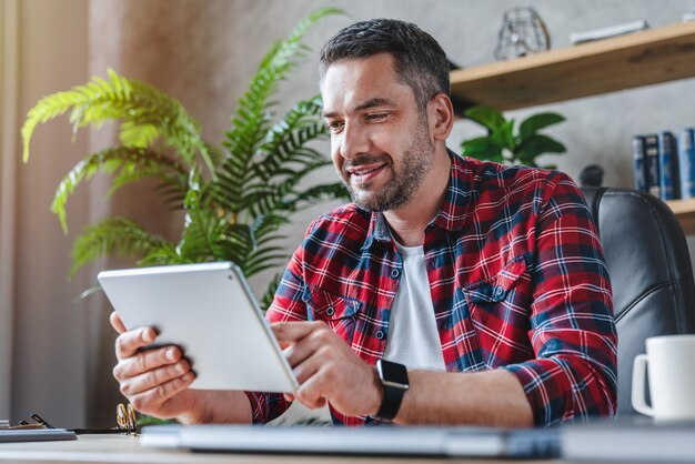 Foto retrato de um homem de meia-idade usando um tablet em casa