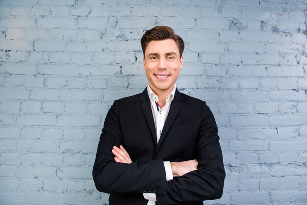 Retrato de um homem de negócios bonito com um sorriso radiante e mãos cruzadas