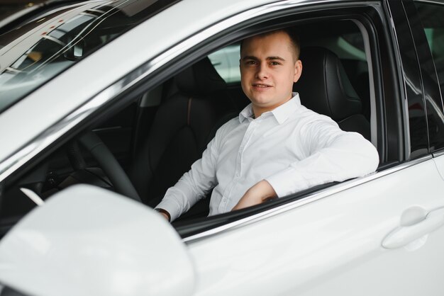 Retrato de um homem de negócios bonito e sorridente dirigindo seu carro