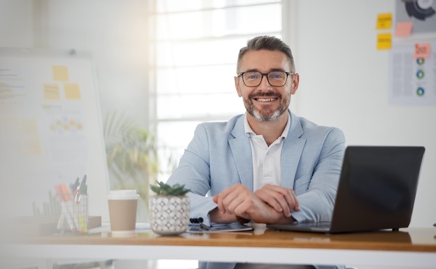 Retrato de um homem de negócios na mesa do escritório com um sorriso, laptop e tablet no site de negócios, relatório on-line ou mídia social, aplicativo digital da Internet e homem maduro confiante com oficina e programação da web