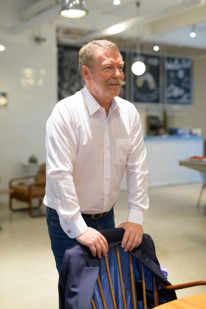 Retrato de um homem de negócios sênior bonito com bigode na cafeteria