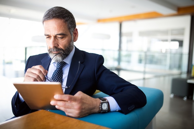 Retrato de um homem de negócios sênior bonito com tablet digital no escritório modren