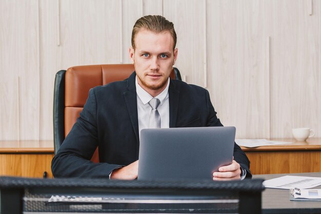 Retrato de um homem de negócios usando um laptop enquanto está sentado na mesa no escritório