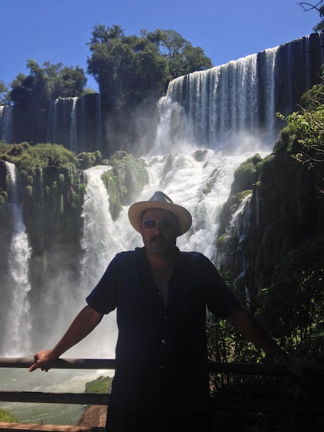 Foto retrato de um homem de pé contra uma cachoeira na floresta