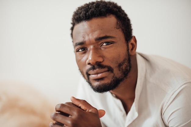 Foto retrato de um homem de pele escura bonito e sincero posando em casa com iluminação natural