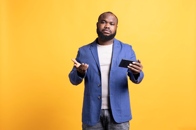 Retrato de um homem desapontado segurando um telefone no fundo do estúdio