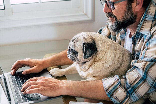 Retrato de um homem e um cachorro trabalhando juntos em casa com o conceito de computador laptop de estilo de vida de trabalho inteligente livre pessoas caucasianos digitando no teclado na estação de trabalho moderno trabalho online negócios vida digital