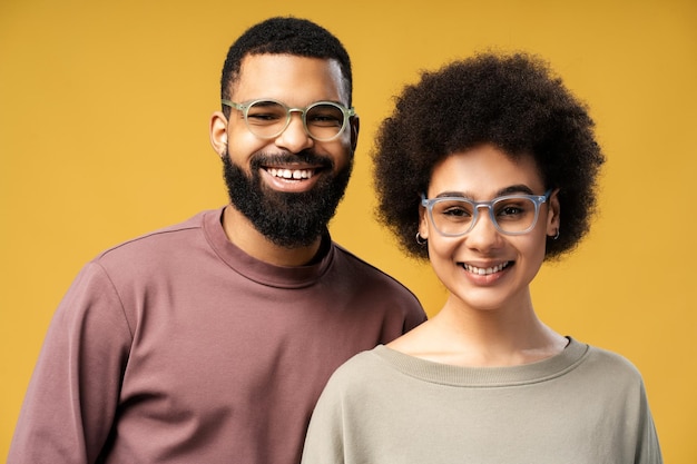 Foto retrato de um homem e uma mulher afro-americanos felizes sorrindo usando óculos olhando para a câmera